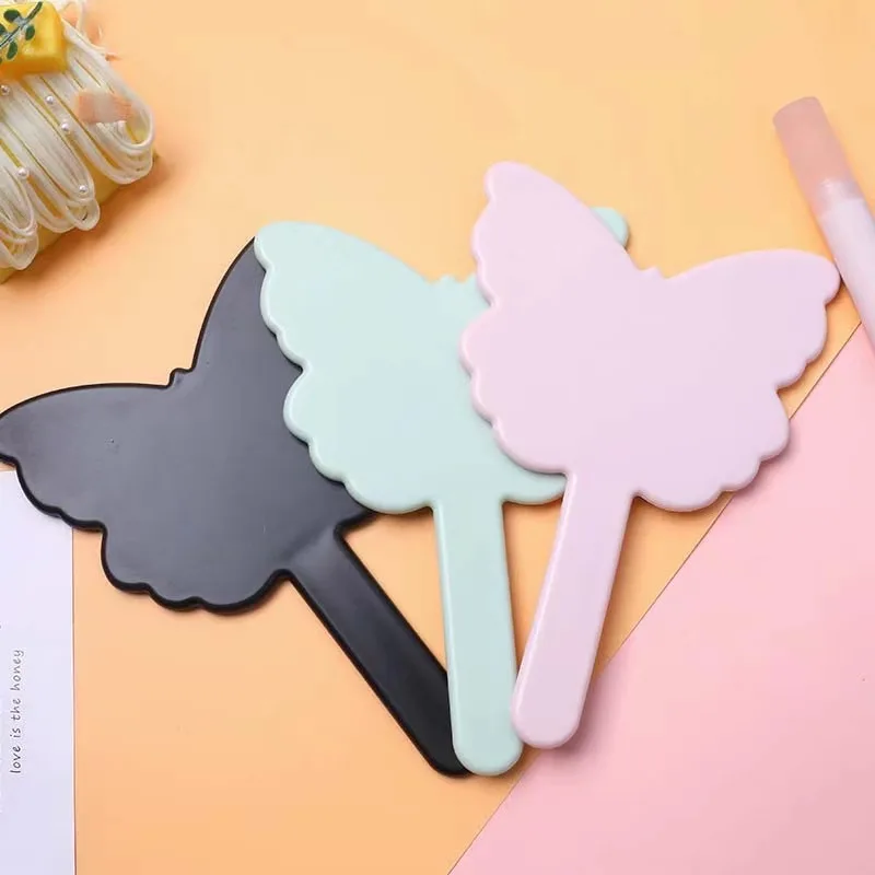 Butterfly-shaped hand mirrors in black, mint and pink