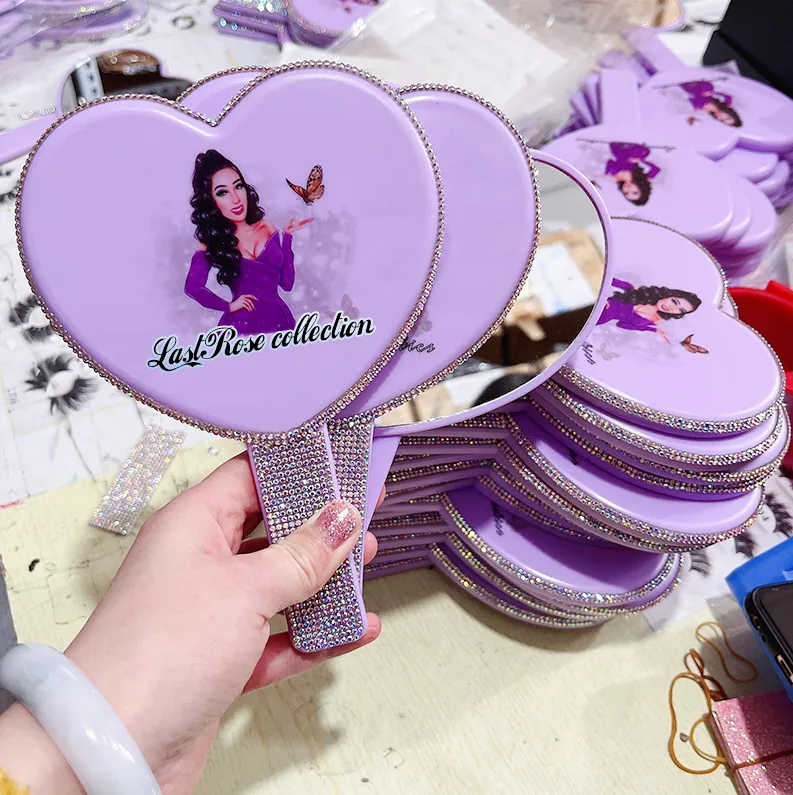 Lavender heart-shaped hand mirror with rhinestone trim and printed artwork