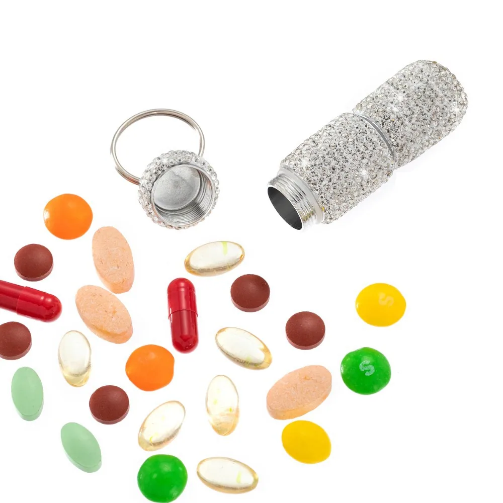 Open silver rhinestone pill box keychain beside assorted tablets