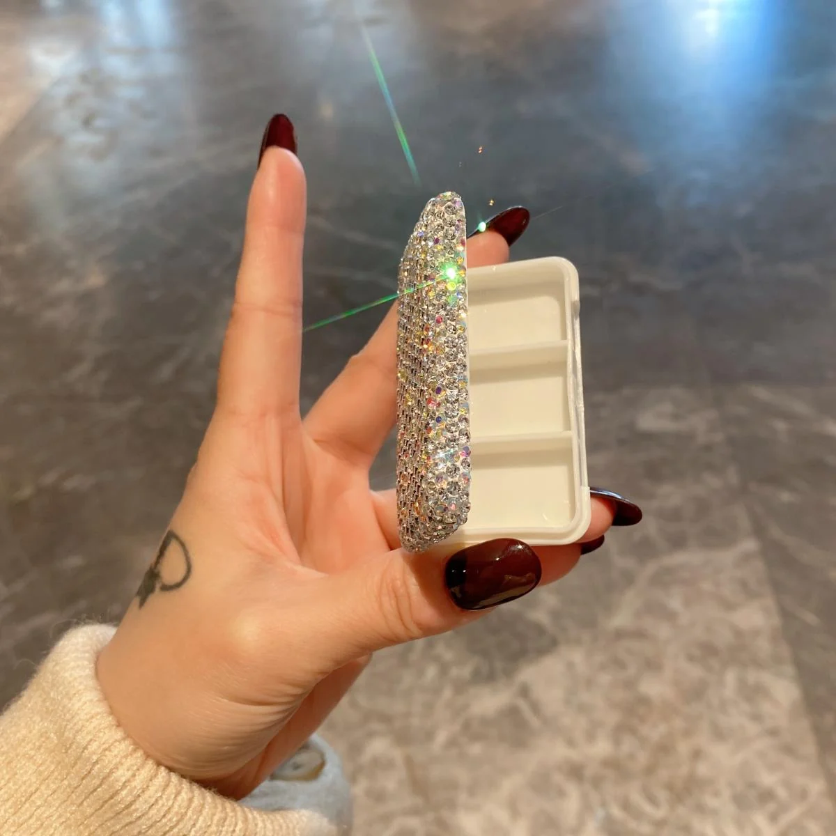 Three-compartment rhinestone pill box opened in hand